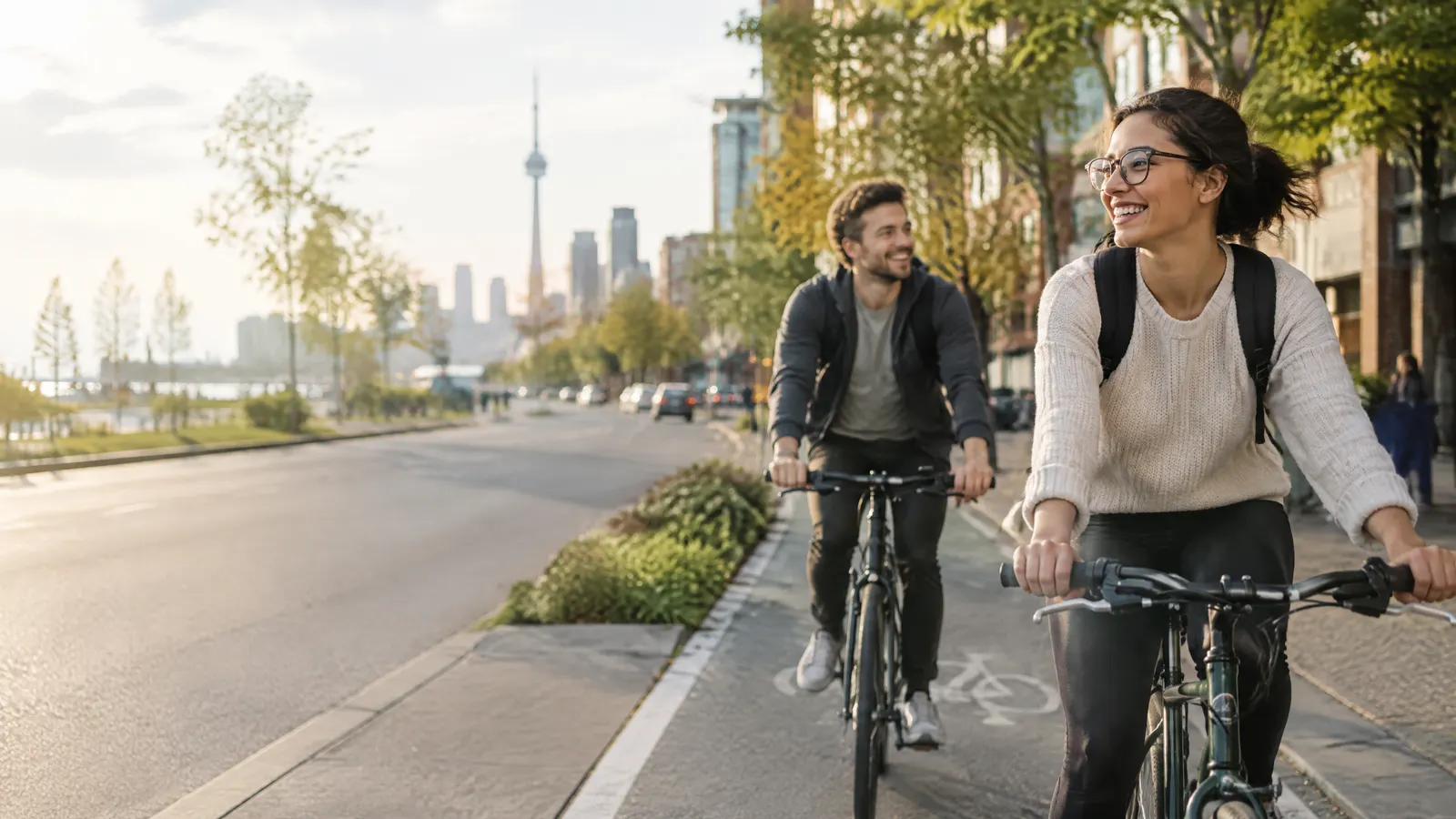 A young couple on bikes in a bike lane on an Ontario main street, one wearing new glasses, active lifestyle.