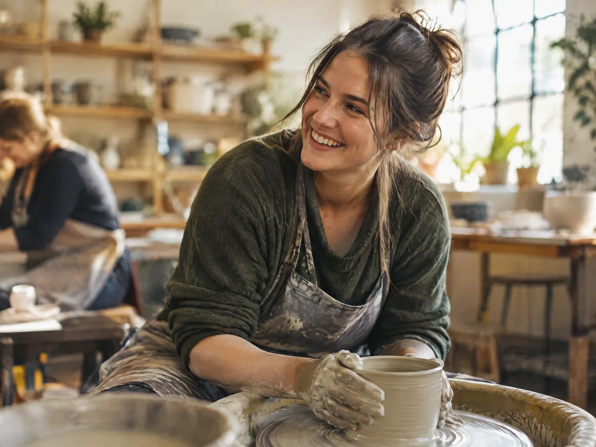 A teacher doing a pottery class on the weekend, smiling.