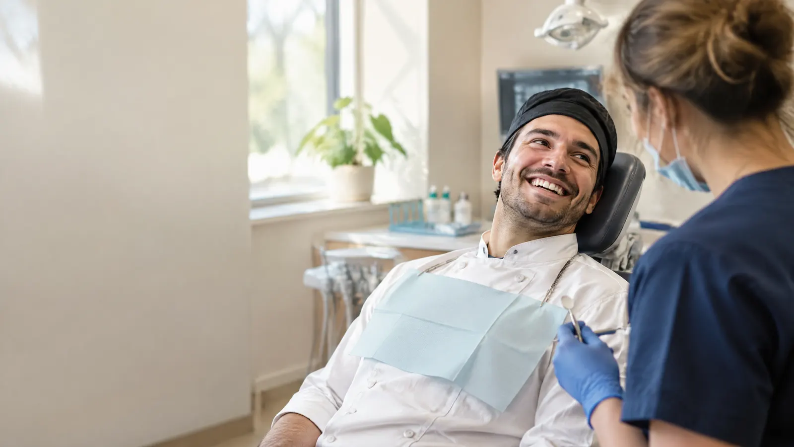 A line cook in chef whites at the dentist, giving a big smile to the hygienist.