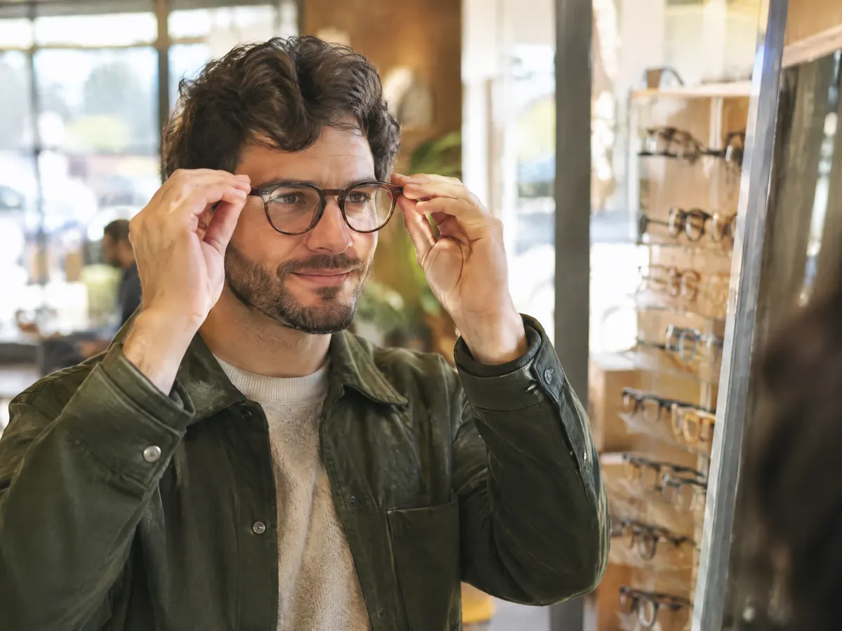 A man trying on new glasses at a Burlington optical shop.