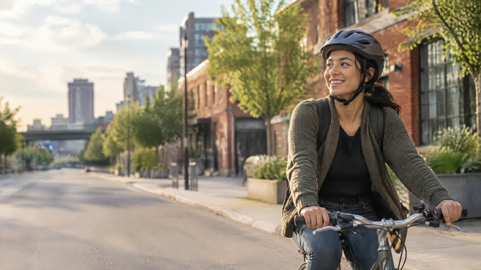A tech worker biking past brick buildings in Kitchener-Waterloo after a dentist appointment, smiling.