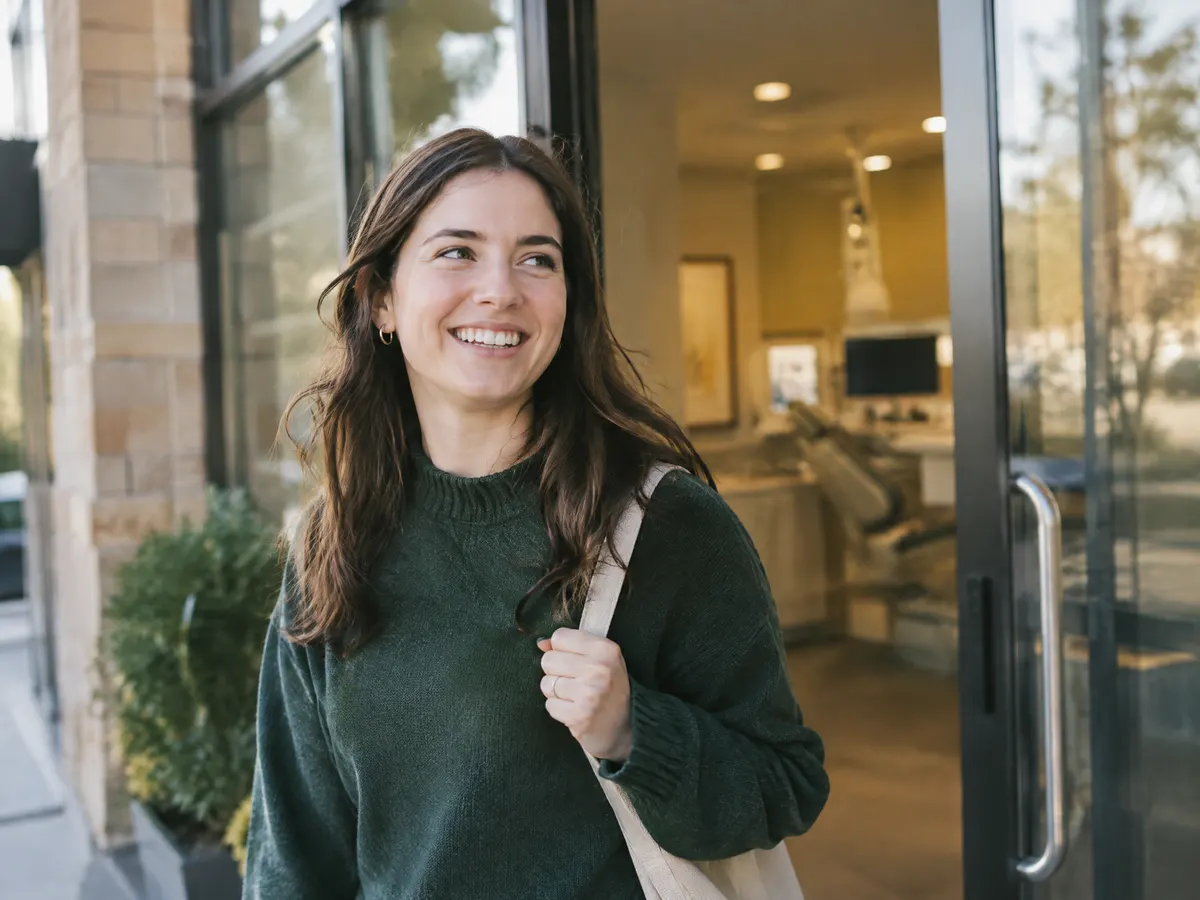 A student-age woman leaving a dental clinic in London Ontario, smiling.