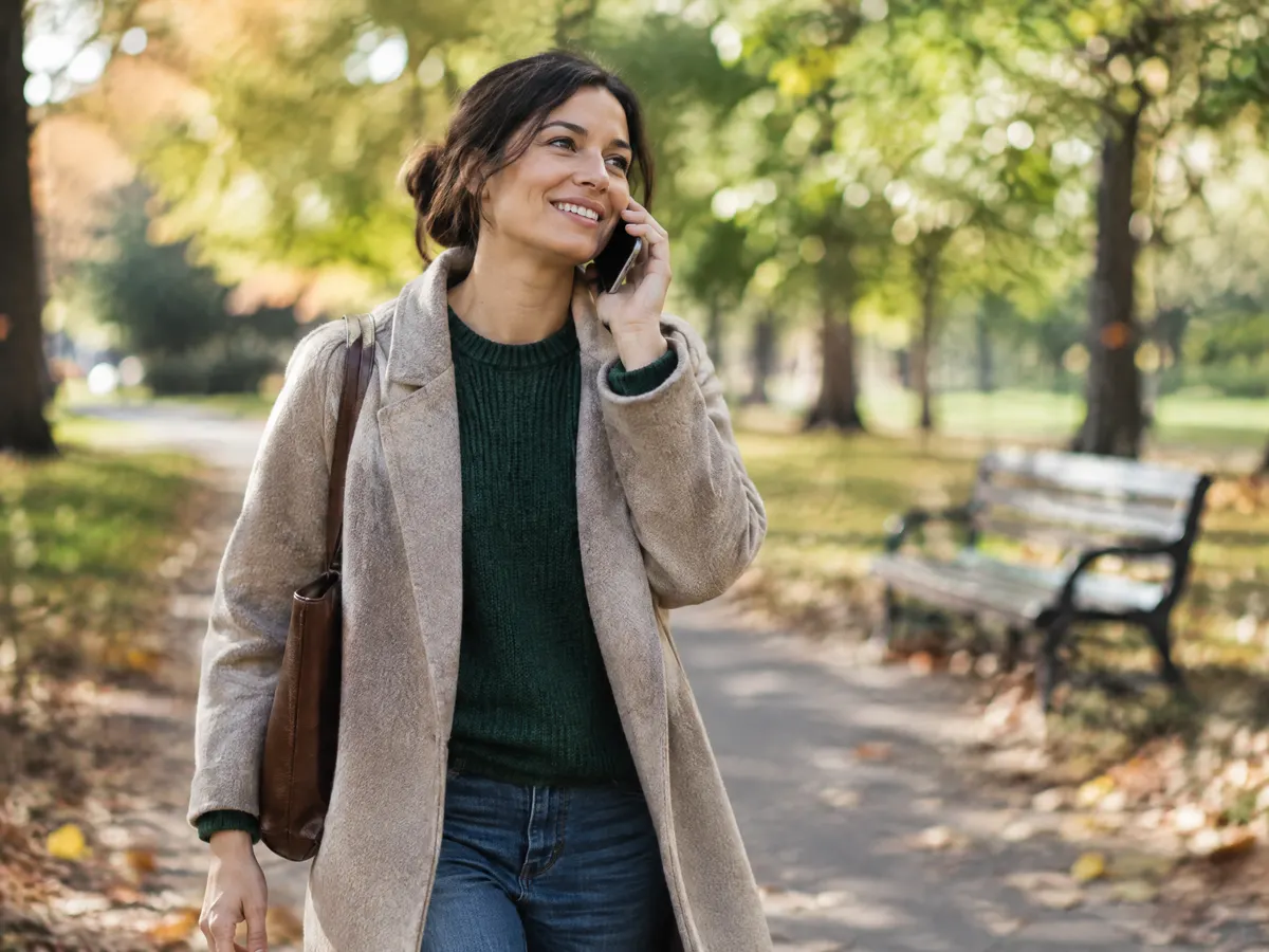 A small business owner taking a walk in a park while chatting on the phone, looking relieved.